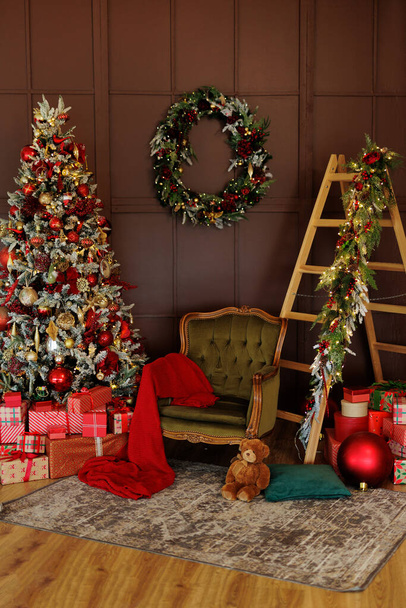 Крісло, драбина і ялинка з червоними подарунками у вітальні - Фото, зображення