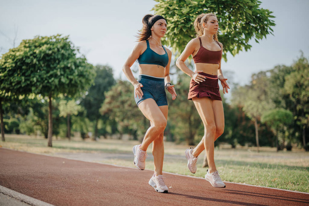 フィットネスフレンズ:アウトドアワークのモチベーションのために自然の中でジョギングする女性を鼓舞 - 写真・画像