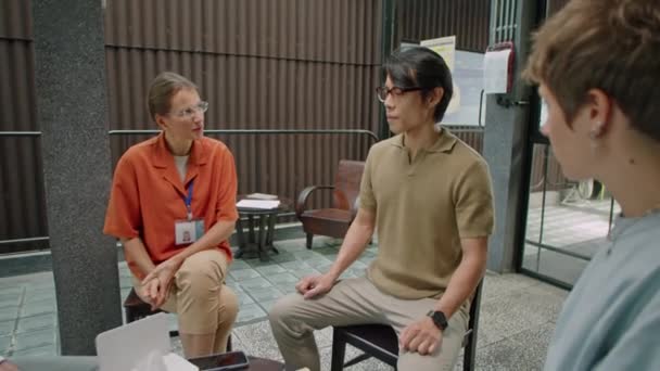 Asijský muž sedí v kruhu s psychology a dalšími pacienty a vypráví o duševních problémech během skupinové terapie - Záběry, video