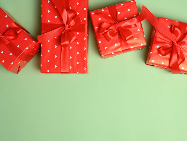 Коробки упакованы в красную бумагу и завязаны лентой на зеленом фоне, подарки. Копирование пространства - Фото, изображение