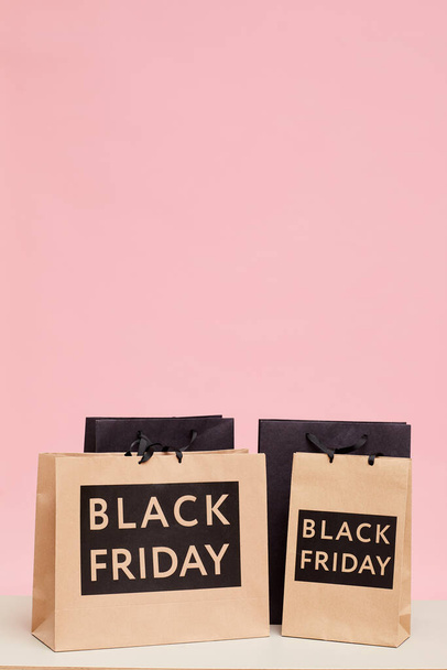 Background image of shopping paper bags with Black Friday lettering against pink wall in womens store - Zdjęcie, obraz