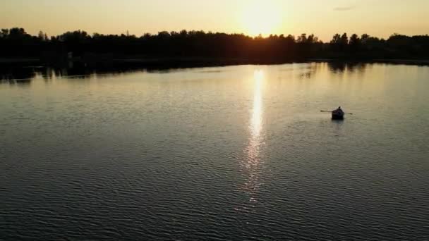 太陽の湖のボートの上に低い空中無人機の眺め. 湖でサンセットカヤック. 穏やかな夏の夕方に野生の自然の中でスポーツ活動. バックグラウンドで日差しのあるボートで愛の物語. - 映像、動画