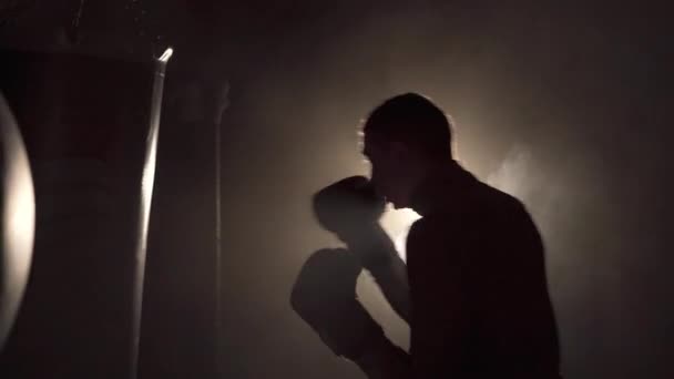 Strength, attack and motion concept. Boxer over dark gym background. Athlete in black gloves. Sporty young man during boxing. Copy space - Footage, Video