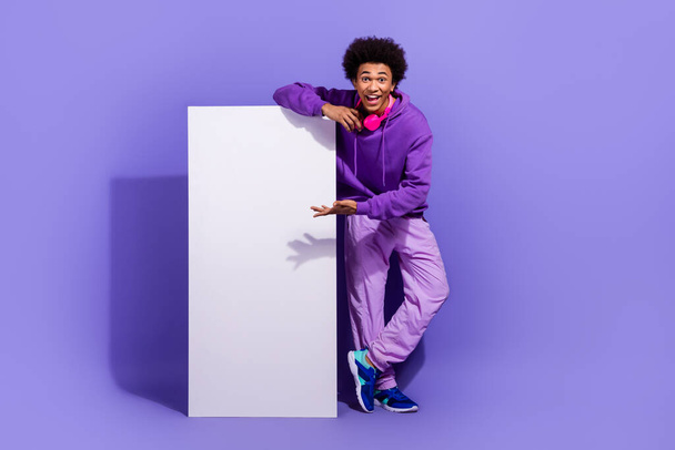 Full size foto van extatische man gekleed stijlvolle pullover violet broek demonstreren smartphone display geïsoleerd op paarse kleur achtergrond. - Foto, afbeelding