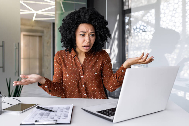 Dissatisfied and disappointed sad woman at workplace looking at laptop, reading online email notification, businesswoman upset and confused sitting inside office. - Foto, Bild