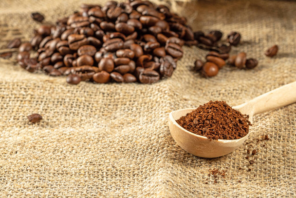 Thème café. Une pile de grains de café et une cuillère en bois avec des granulés de café moulus. - Photo, image