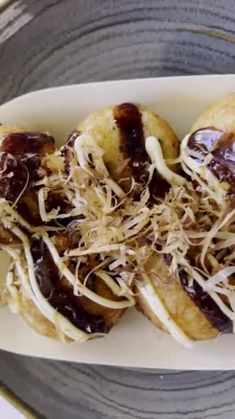 Köstliche japanische Köstlichkeiten: Nahaufnahme über traditionellem Takoyaki, einem Streetfood mit pikanten Soßen, cremiger Mayonnaise und tanzenden Bonito-Flocken (Katsuobushi-Flocken)) - Filmmaterial, Video