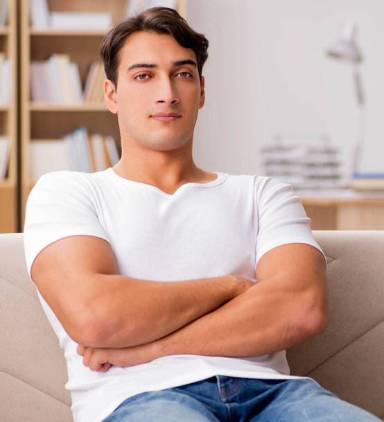 Молодий чоловік розслабляється сидячи в дивані
 - Фото, зображення