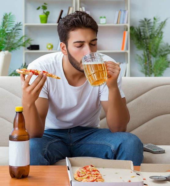 El hombre comiendo pizza teniendo una comida para llevar en casa descansando relajado - Foto, Imagen