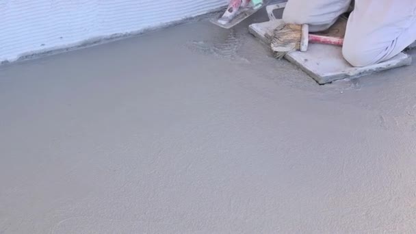 Operaio qualificato del cemento che utilizza cazzuola sul pavimento di cemento fresco bagnato in cantiere - Filmati, video