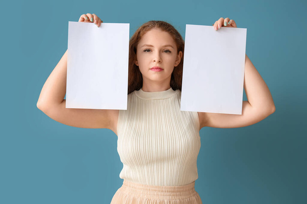 Young woman with blank paper sheets on blue background - Photo, Image