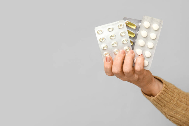 Vrouwelijke hand met pillen op grijze achtergrond, close-up - Foto, afbeelding