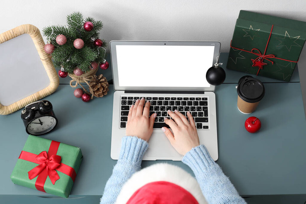 Woman working with laptop in office on Christmas eve, top view - Photo, Image