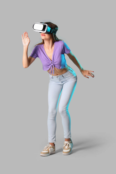 VR szemüveget használó fiatal nő világos háttérrel - Fotó, kép