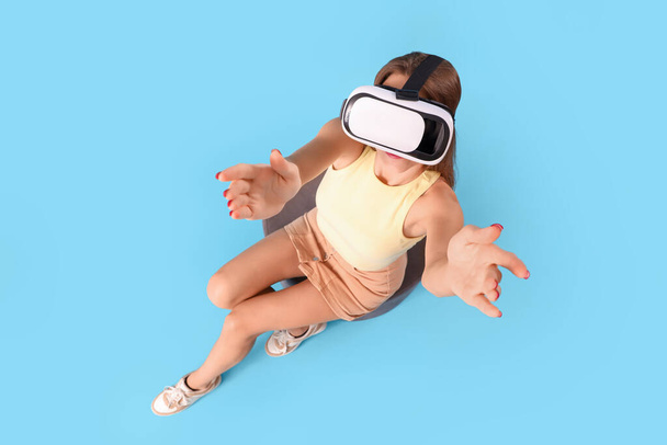 Fiatal nő használ VR szemüveg kék háttér, felső nézet - Fotó, kép