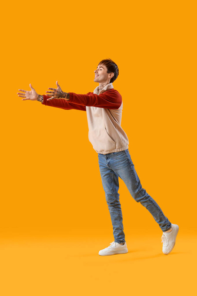 Young man opening arms for hug on yellow background - Photo, Image