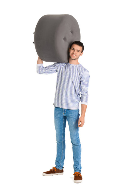 Young man carrying pouf on white background - Photo, Image