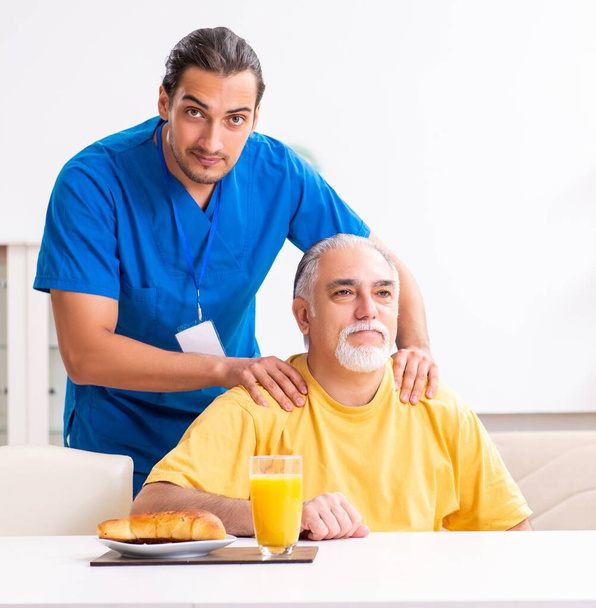 A fiatal férfi orvos meglátogatja idős beteg otthon - Fotó, kép