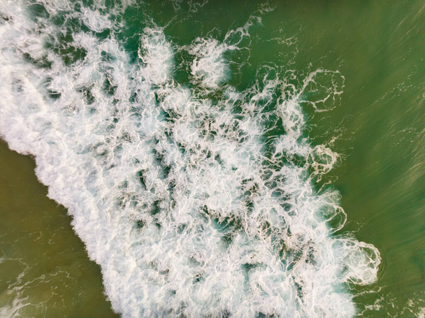 Luftaufnahme von Wellen krachend auf Sandstrand, Meeresoberfläche Ozeanwellen Hintergrund, Draufsicht Strand Hintergrund - Foto, Bild