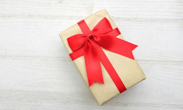 a bird's eye view of photo of  gift box  white with red ribbon bow isolated on a white on the wooden table with empty space - Photo, Image