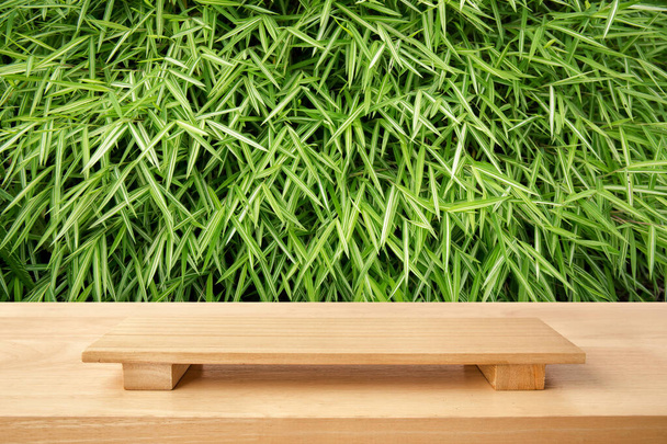 Lege sushi bord op houten tafel met bamboe groene bladeren achtergrond. Bovenaanzicht van plankenhout voor grafische standaard, interieur ontwerp of montage toon uw voedingsproduct van cultuur China en Japan. - Foto, afbeelding