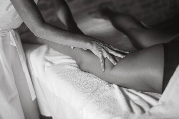 επαγγελματίας καυκάσιος γυναίκα φυσιοθεραπεύτρια μασέρ εκτελεί μασάζ ποδιών σε ισπανόφωνη λατίνο μελαχρινή γυναίκα σε spa κλινική - Φωτογραφία, εικόνα