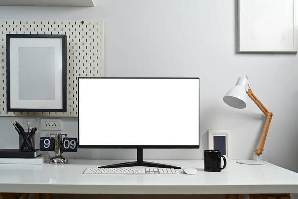 Přední pohled prázdný monitor, lampa, hodiny, knihy a šálek kávy na bílém stole. - Fotografie, Obrázek
