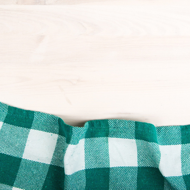зеленая сложенная скатерть поверх отбеленного деревянного стола
 - Фото, изображение