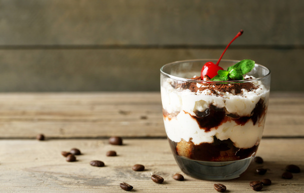 Tasty tiramisu dessert in glass, on wooden background - 写真・画像