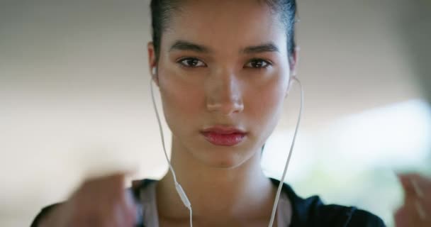 Face, fitness and woman with earphones for running, exercise and healthy workout in city. Portrait, serious runner and listening to music for cardio performance, power and sports training outdoor. - Footage, Video