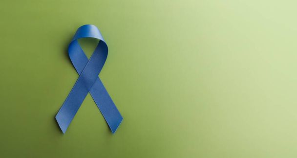 Eturauhassyövän valistuskampanja. Terveydenhuolto. Lähikuva sininen nauha makaa vihreällä taustalla, Top View - Valokuva, kuva