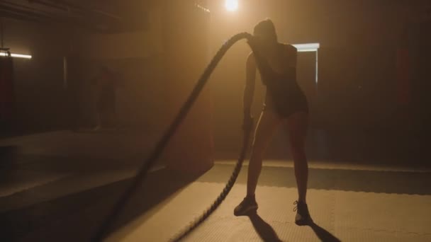 Largo tiro de atleta femenina haciendo ejercicio de cuerda de batalla mientras el brazo de entrenamiento bíceps y el cuerpo - Metraje, vídeo
