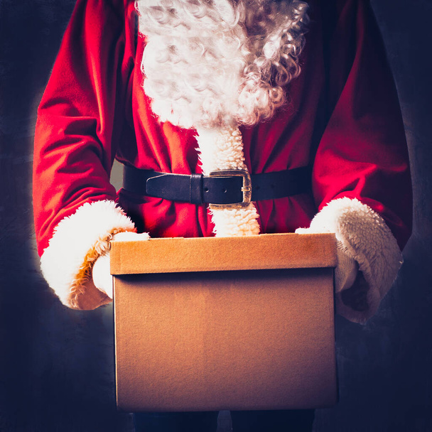 Detailní záběr rukou Santa Clause s balíčkem, kartónovou dárkovou krabicí, kde můžete psát čísla nebo text. - Fotografie, Obrázek