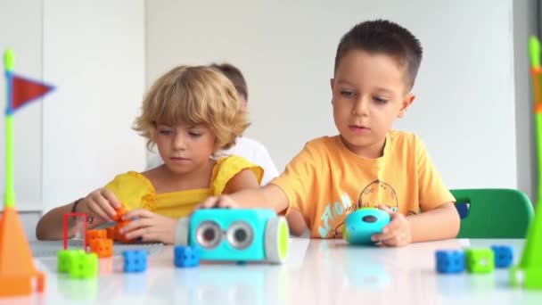 Niños de edad elemental jugando con coche de juguete electrónico con joystick en el curso de educación tecnológica. Desarrollo infantil, educación, motricidad fina - Metraje, vídeo