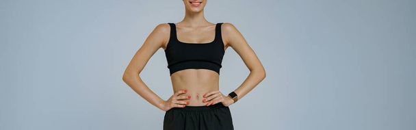 Smiling fitness woman wearing sportswear looking at camera on studio background. High quality photo - Foto, Imagen