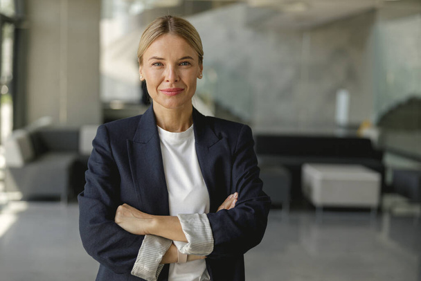 Portret van een zelfverzekerde zakenvrouw met gekruiste handen op kantoor en kijkt camera - Foto, afbeelding