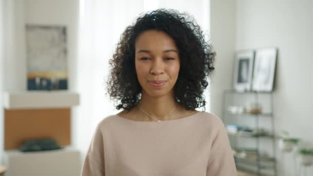 Portrét krásné stylové bi rasové africké Američanky usmívající se na kameru, která vypadá sebevědomě. Nošení moderní elegantní ležérní oblečení v moderním městském apartmánu pozadí. Skuteční lidé série 4K - Záběry, video