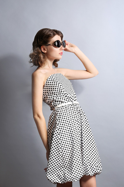 Ritratto di bel modello in dots dress in occhiali da sole su sfondo grigio
 - Foto, immagini
