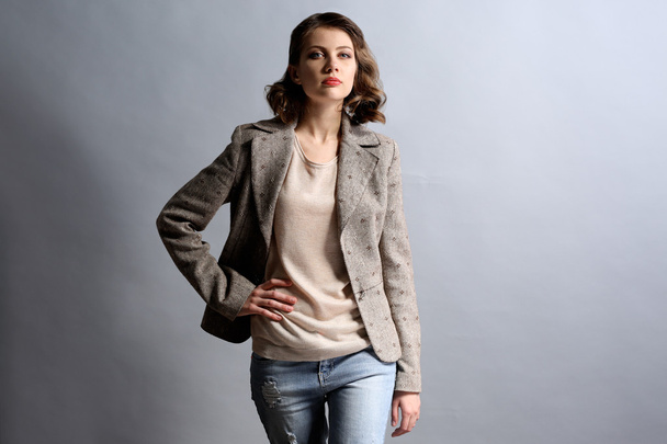 Portrait of beautiful model in jeans and jacket on gray background - Foto, afbeelding