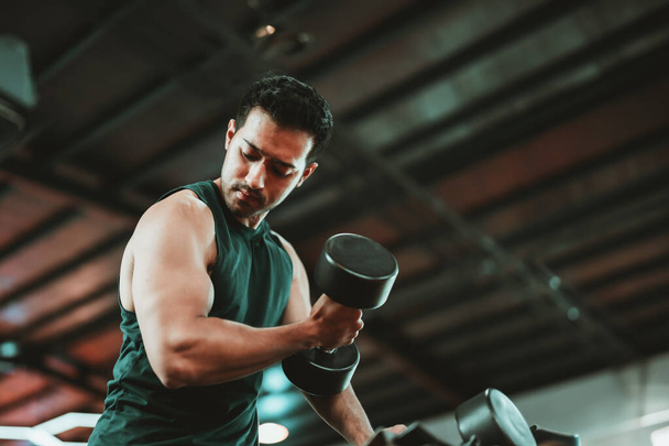 Fiatal ázsiai férfi dolgozik ki Dumbbell egy élénk edzőteremben - Fitness és Wellness koncepció az aktív életmód - Fotó, kép