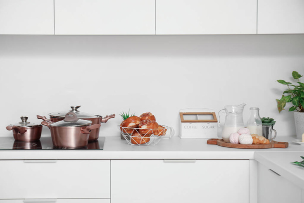 Balcão de cozinha branco com rolos de canela, panelas de cozinha e leite - Foto, Imagem