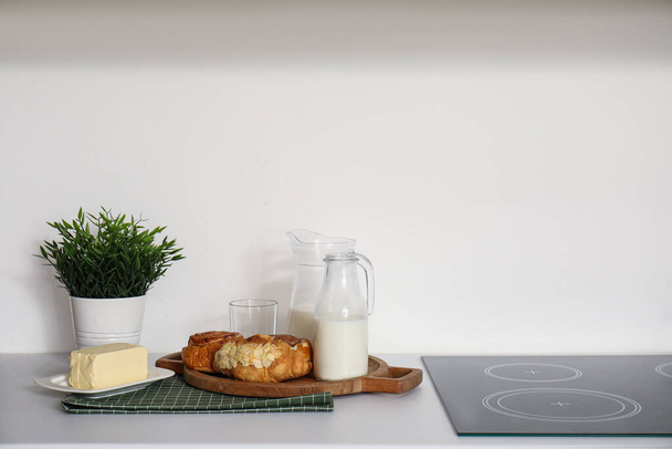 Bord met croissants, melk en boter op witte aanrecht - Foto, afbeelding