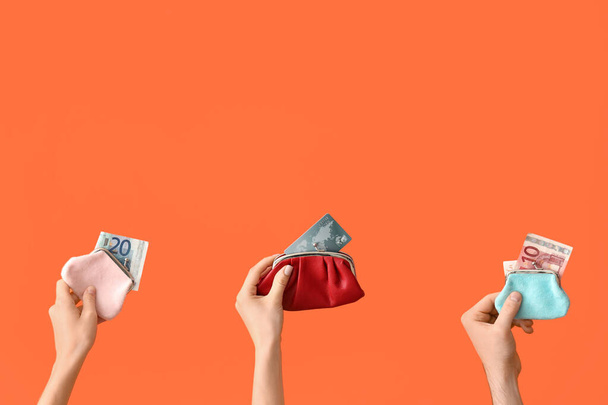 Női kéz pénztárcával és pénzzel narancssárga alapon - Fotó, kép