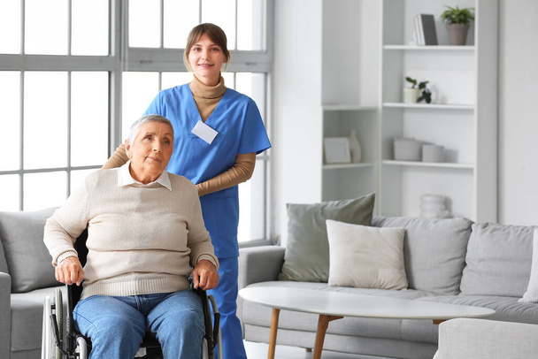 Seniorin im Rollstuhl mit Pflegerin zu Hause - Foto, Bild