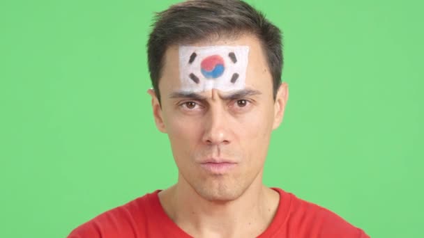 Video in studio con croma del primo piano di un uomo serio con una bandiera sud coreana dipinta sul volto guardando la macchina fotografica - Filmati, video