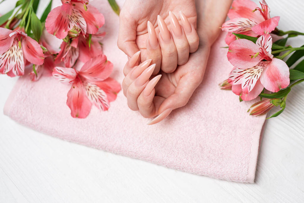 Elegante manicure naturale rosa pastello. Mani femminili con fiori alstroemeria.  - Foto, immagini