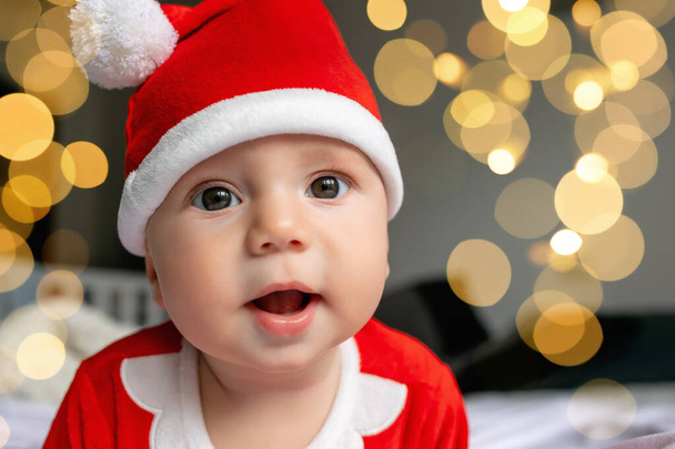 Söpö valkoihoinen vauva 4-5 kuukauden ikäinen Santa puku makaa sängyssä. Hyvää joulua joulu ja onnellista uutta vuotta 2024 - Valokuva, kuva