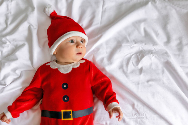 Mattina di Natale, bambino in costume di Babbo Natale, sdraiato sul letto. - Foto, immagini