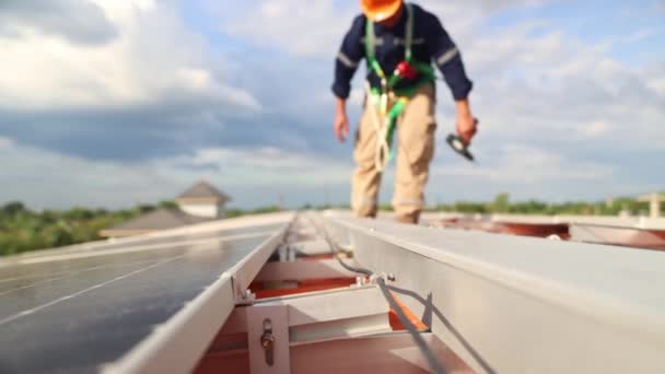 Maszat ázsiai férfi villamosmérnök vizsgálja napelem telepítés acél tető ipari gyár járkál tetőtérben kezében egy elektromos fúró ellenőrizze a fontos pontokat minden napelem. - Felvétel, videó