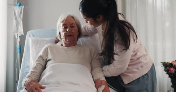 Woman, nurse and patient in elderly care on bed for healthcare, support or rest at the hospital. Female volunteer, caregiver or medical doctor helping sick senior person for comfort at the clinic. - Footage, Video